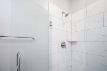 a white tiled shower in a bathroom with a glass door